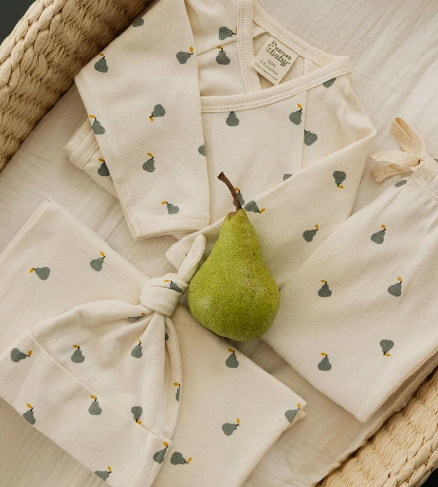 Baby clothing set with a green pear on a textured surface