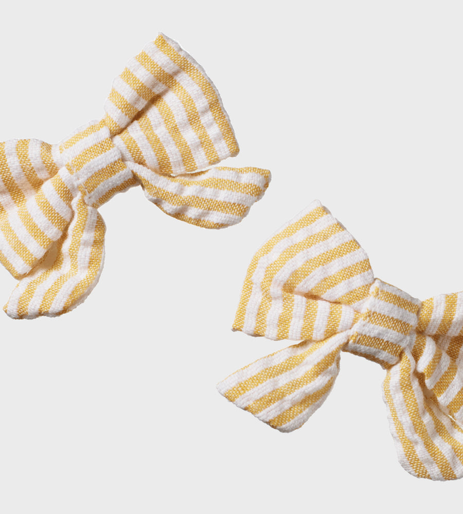 Two yellow and white striped hair bows on a light gray background