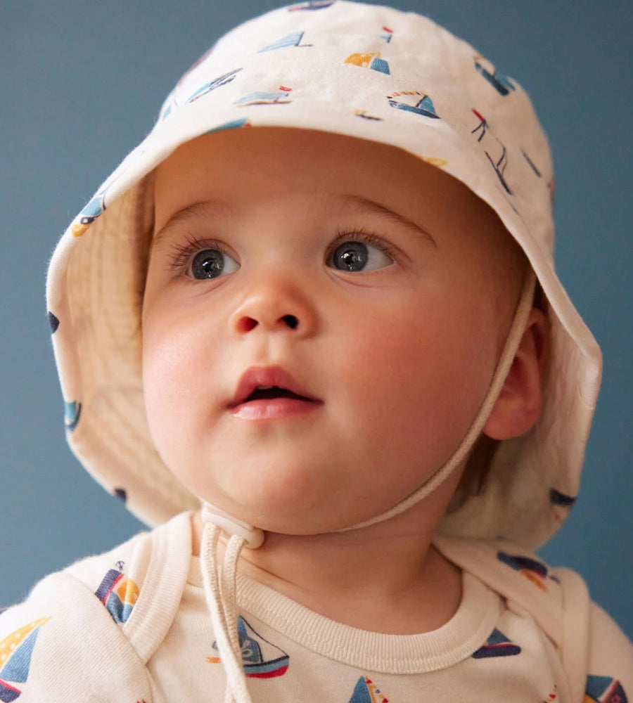 Baby wearing a colorful hat and shirt with a blue background