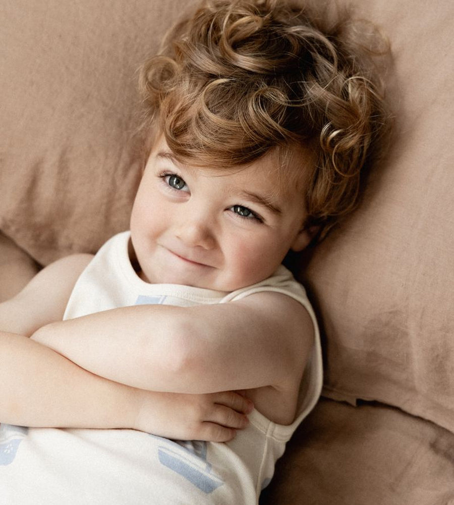Child with curly hair lying on a beige pillow