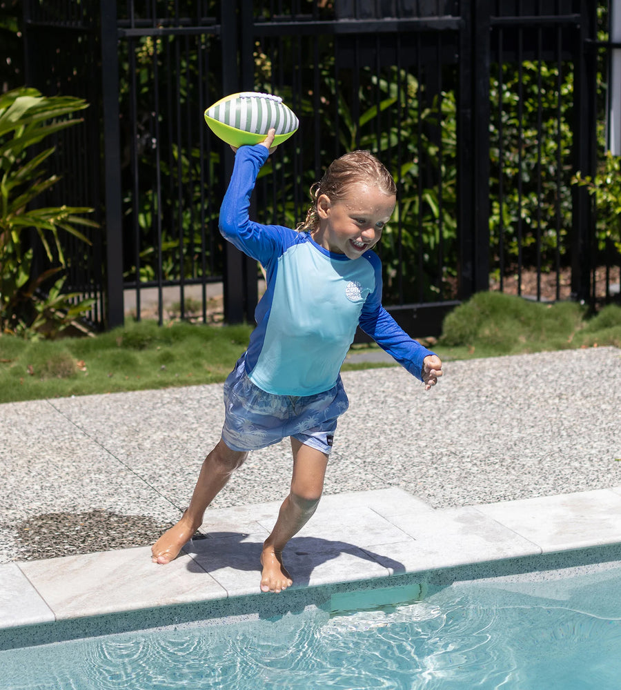 Child playing with a football by a pool