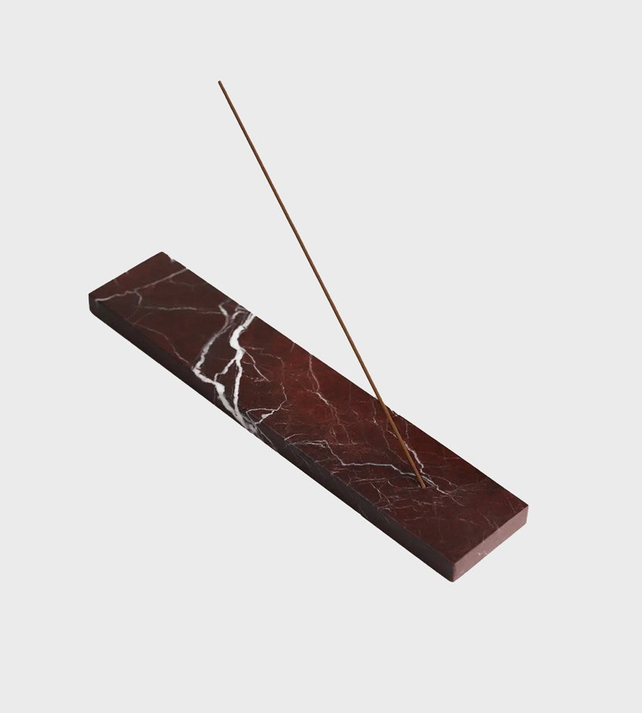 Marble-patterned incense holder with a single incense stick on a light gray background