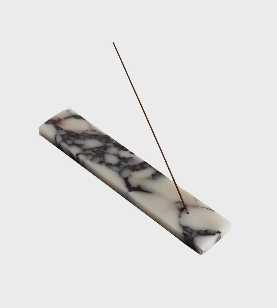 Marble-patterned incense holder with a single incense stick on a white background