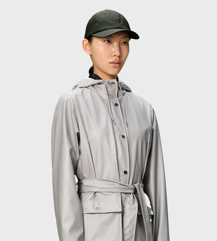 Person wearing a light gray raincoat and dark green cap on a white background