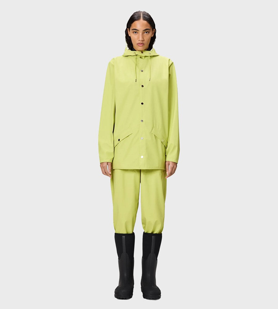 Person wearing a bright green raincoat and pants with black boots on a light gray background