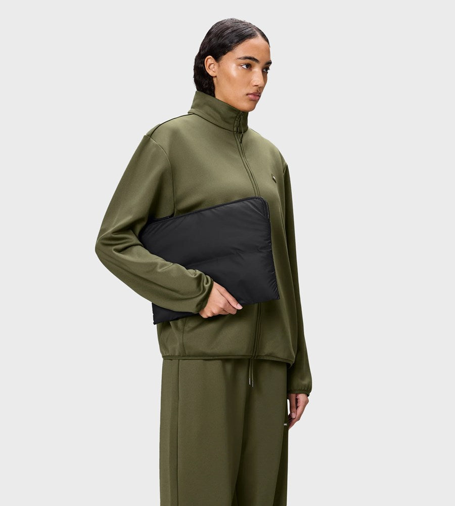Person wearing a green tracksuit with a black panel on a white background