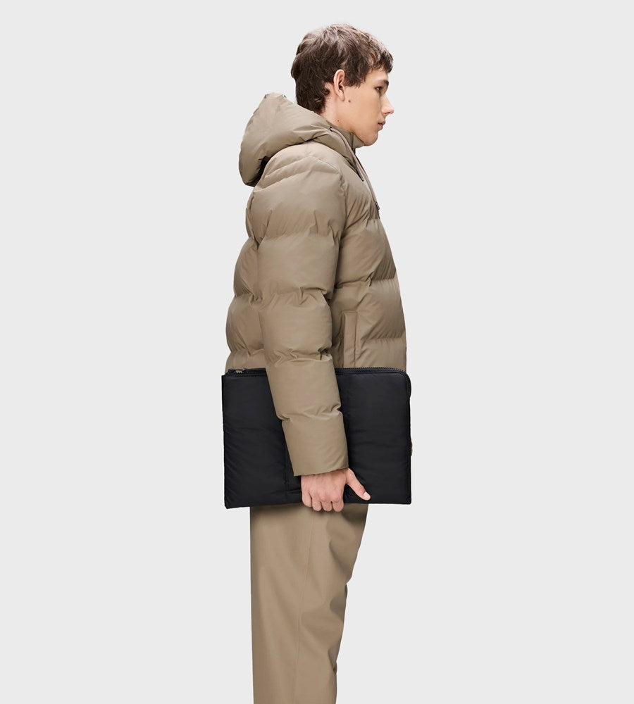 Person wearing a beige puffer jacket with black accents on a white background