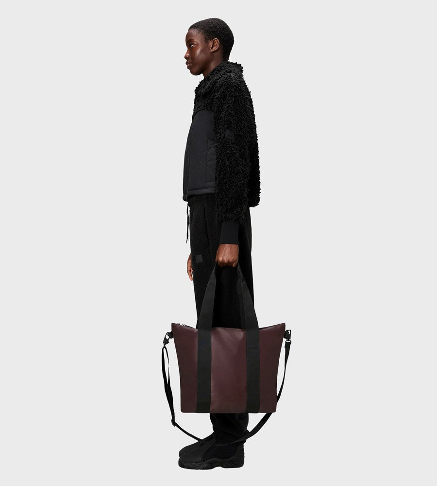 Person holding a large brown leather bag against a white background
