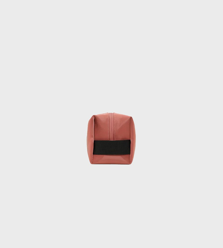 Small pink pouch with a black strap on a light gray background