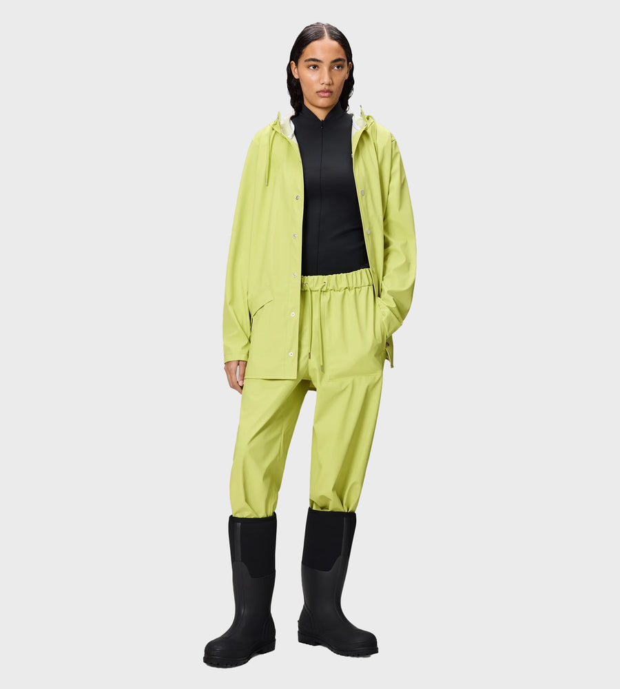 Person wearing a bright yellow raincoat, pants, and black boots on a white background