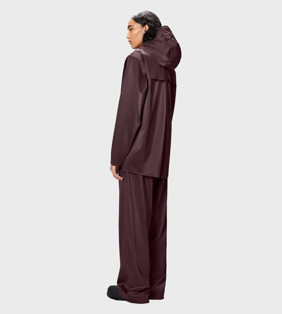 Person wearing a brown raincoat and pants on a white background