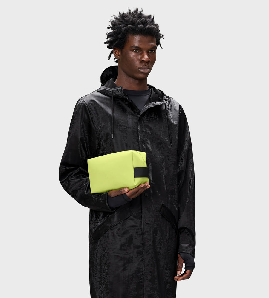 Person wearing a black raincoat holding a yellow item against a white background