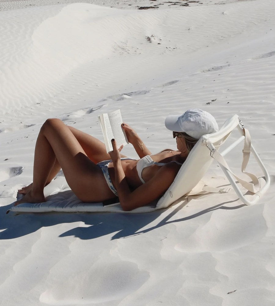 Person reading a book on a white sand beach