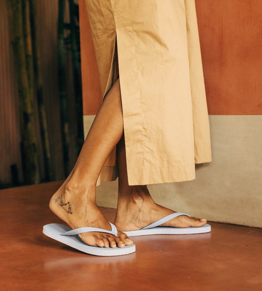 Person wearing white flip-flops with a neutral background