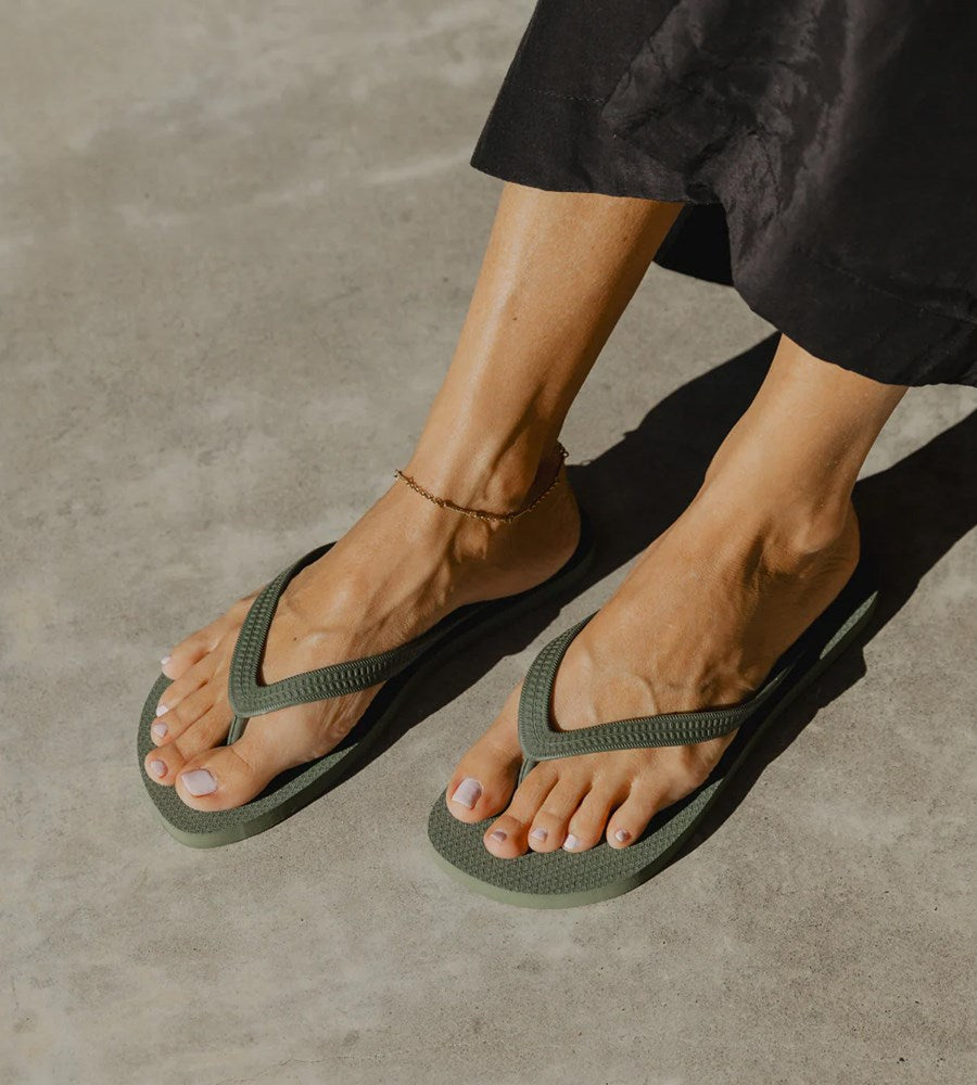 Person wearing green flip-flops on a concrete surface