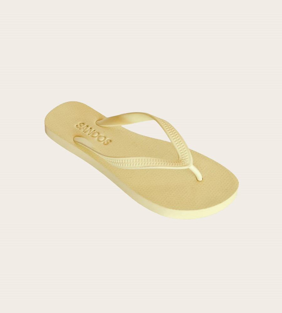 Gold flip-flop sandal on a light beige background