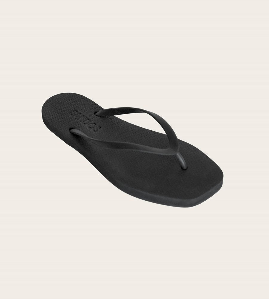 Black sandal with 'Chaco' branding on a beige background
