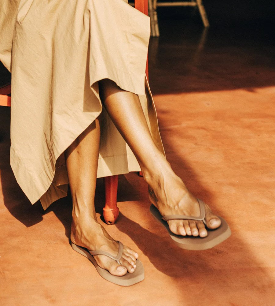 Person wearing beige sandals on a wooden floor