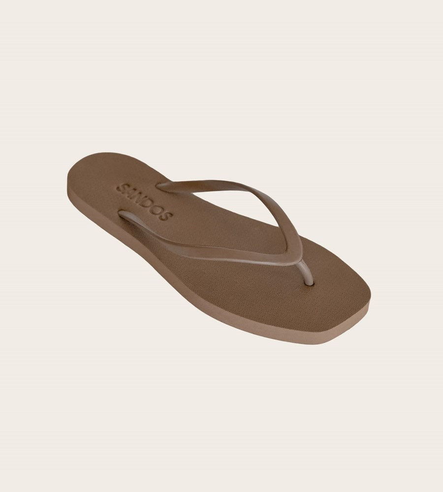 Brown sandal with 'SANDOS' branding on a beige background