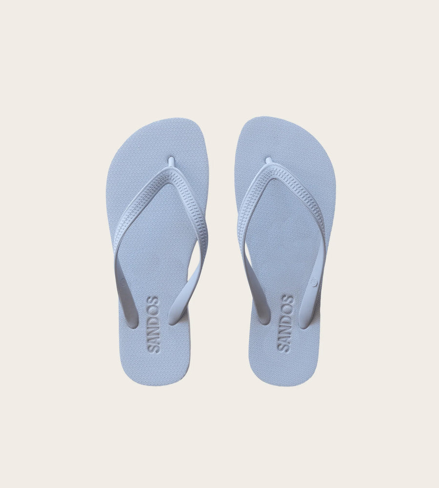 Pair of light blue flip-flops on a beige background