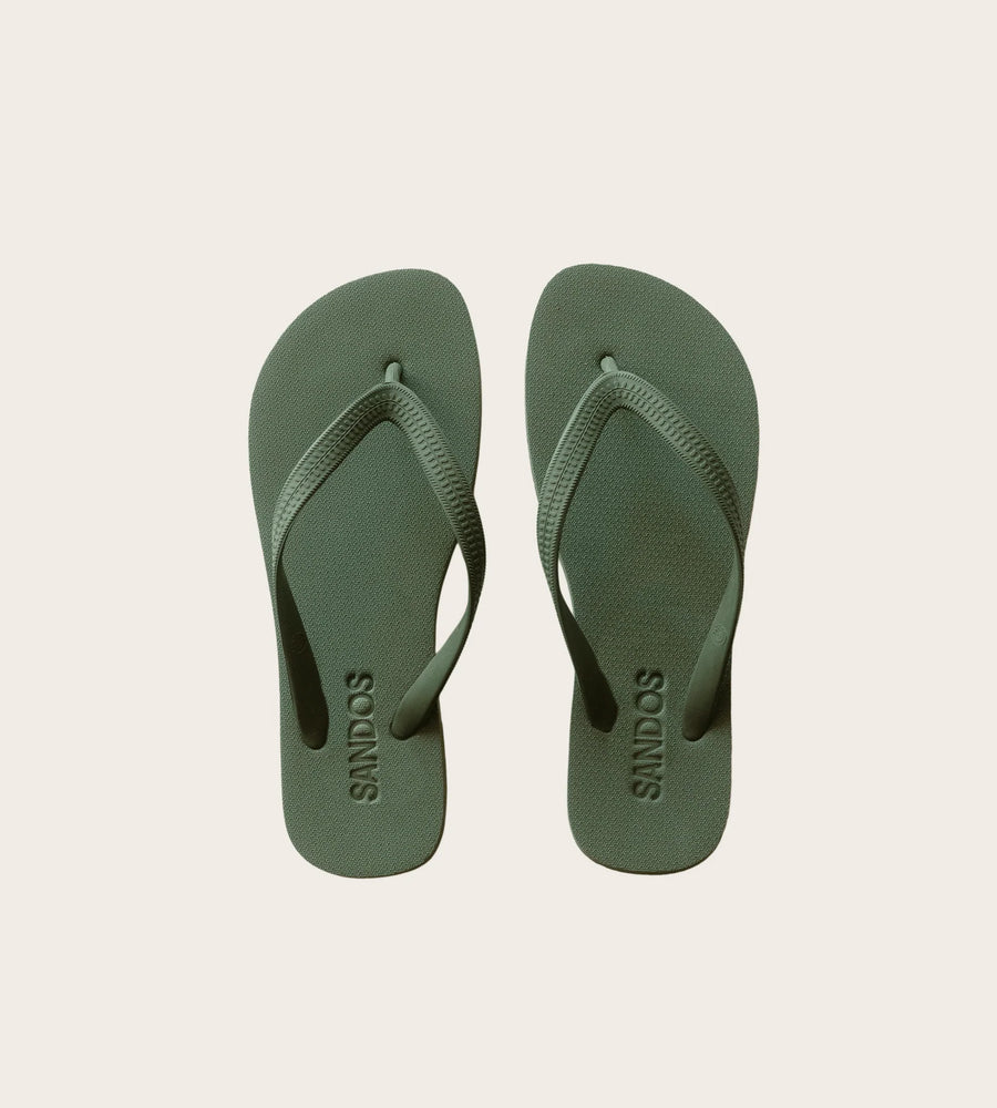 Pair of green flip-flops on a beige background