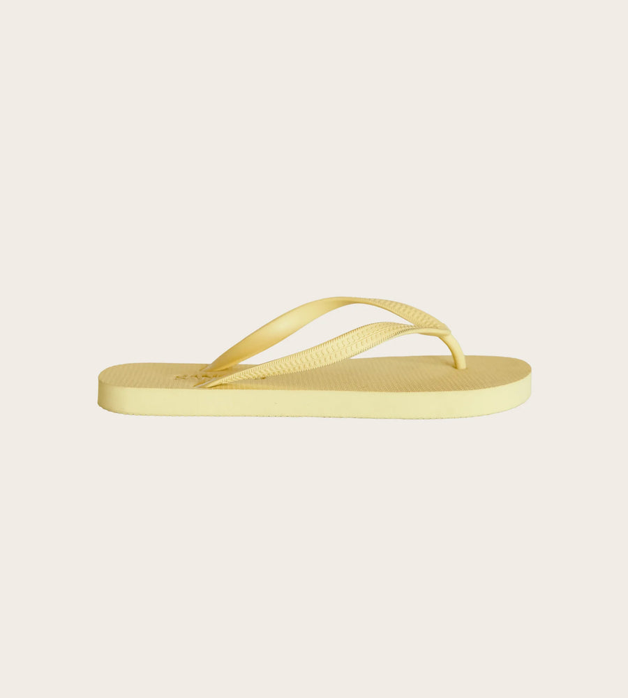 Yellow flip-flop sandal on a light beige background