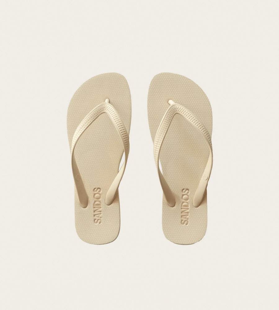Pair of beige flip-flops with 'Sindos' branding on a light gray background
