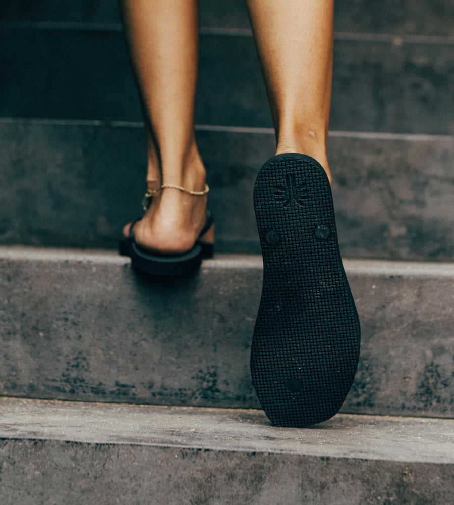 Close-up of a person's foot wearing a black sandal on a step.