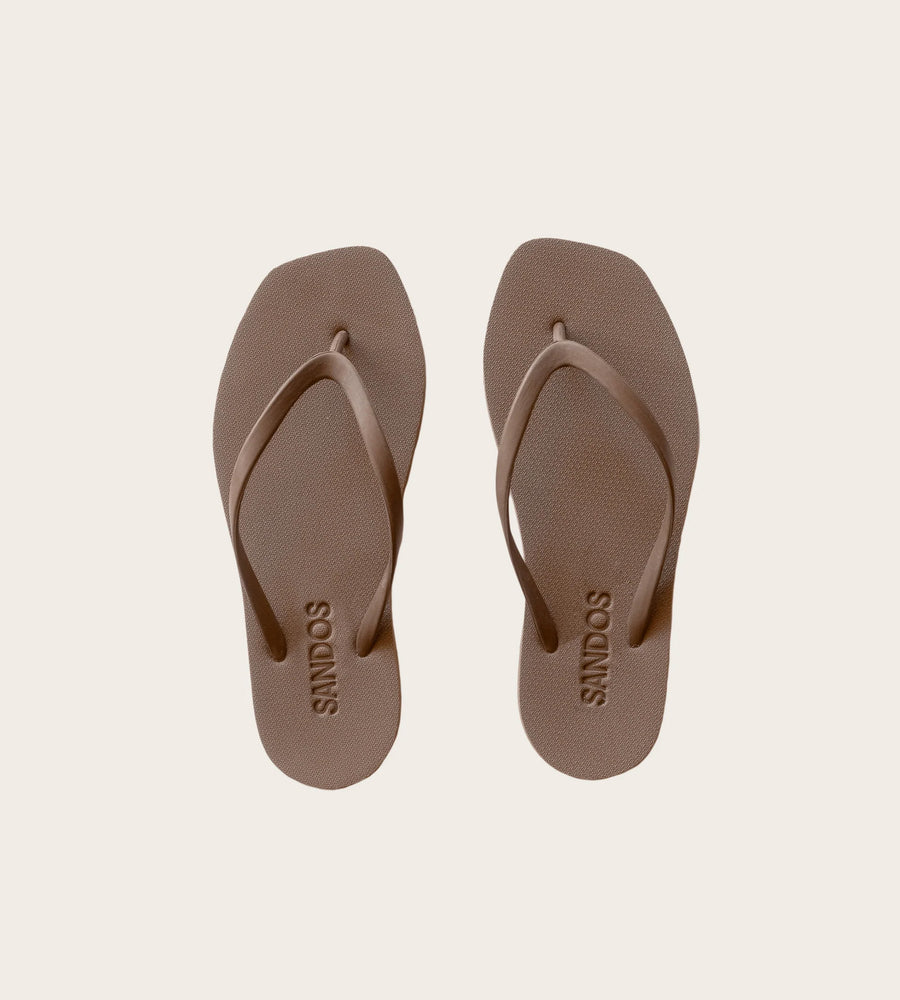 Pair of brown sandals with 'SANDALS' branding on a beige background