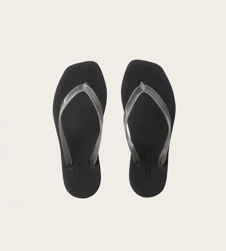 Black flip-flops with a gray strap on a light beige background