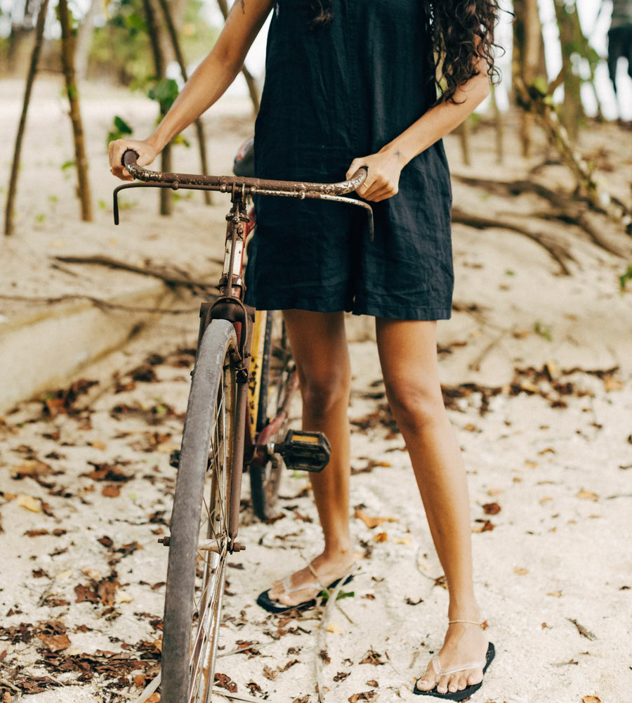 Person holding a bicycle on a sandy path with trees in the background