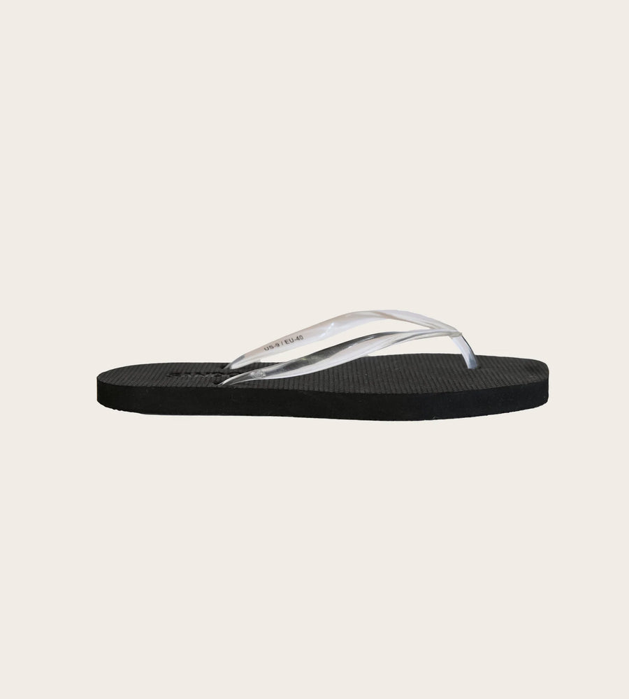 Black sandal with a clear strap on a beige background