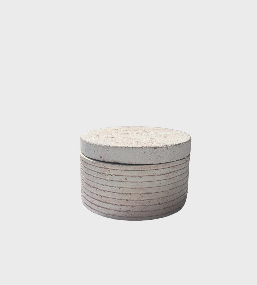 Round concrete ottoman with a textured surface on a light gray background