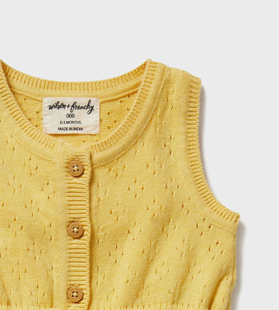 Yellow baby cardigan with button details on a white background