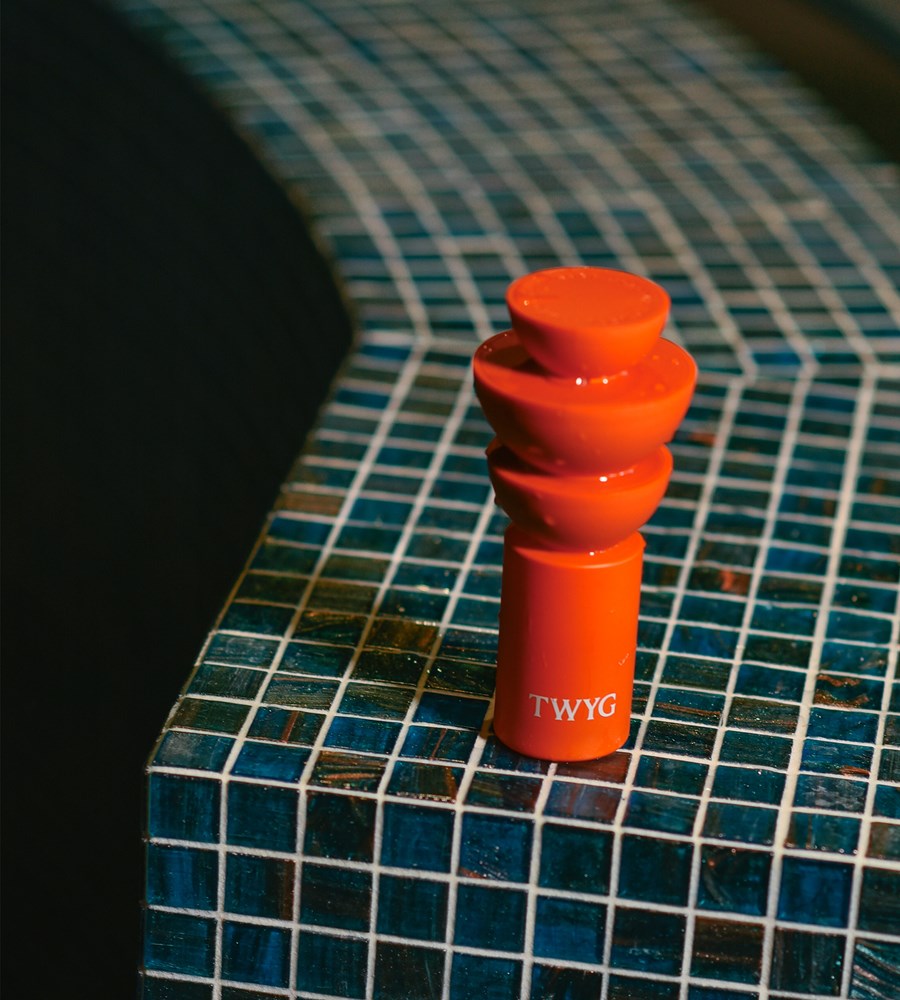 Red bottle with 'TWYG' branding on a blue tiled surface