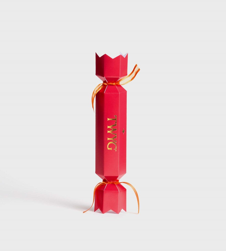 Red Christmas cracker with gold ribbon on a light gray background