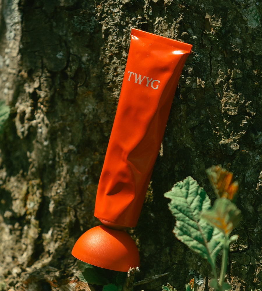 Orange product with 'TWYG' branding attached to a tree