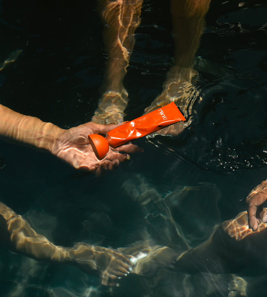 Person holding an orange object underwater with feet visible in the background