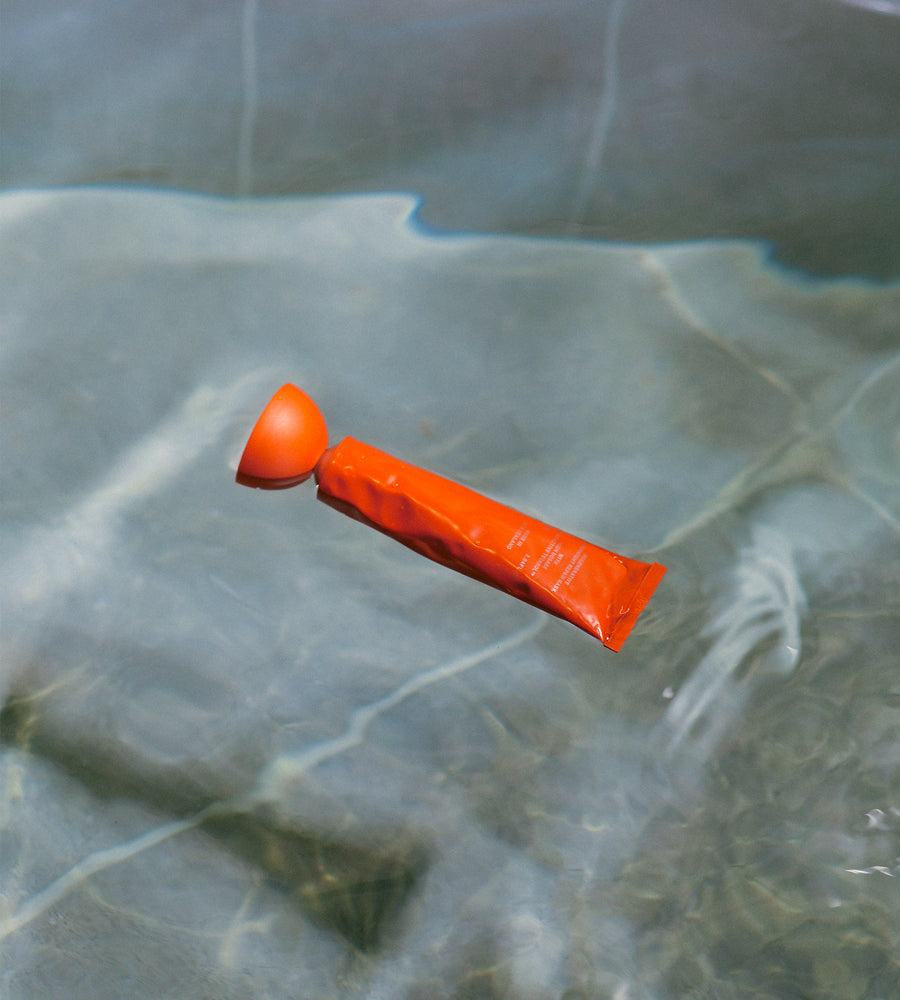 Orange object floating on water with a leafy green background