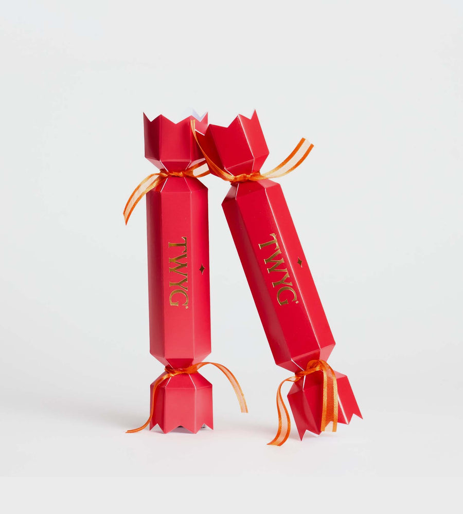Two red cracker-like packages with orange ribbons on a white background