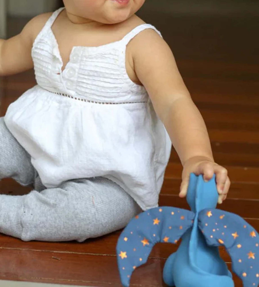 Child holding a blue toy with star patterns on a wooden floor.