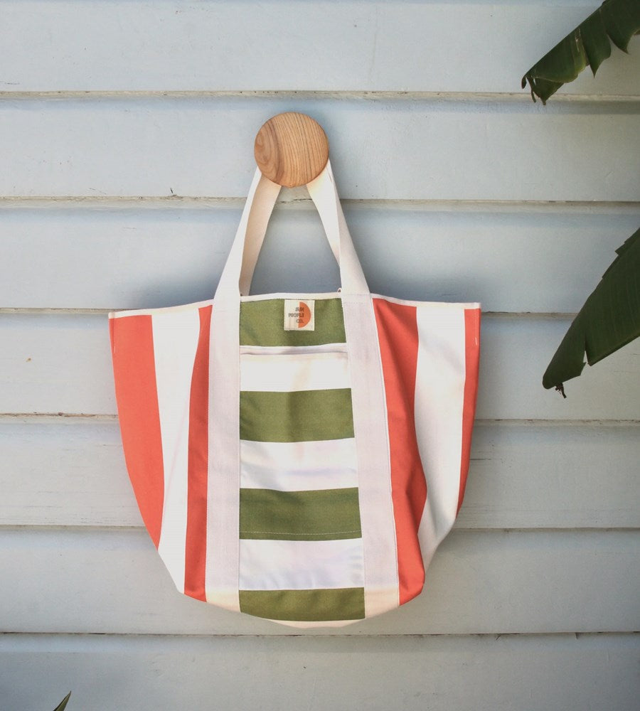 Striped tote bag with wooden handle on a wooden surface
