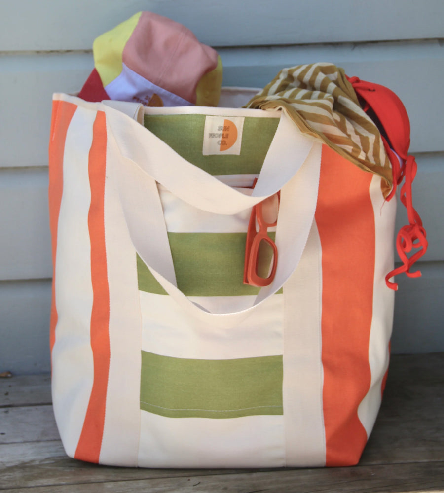 Striped tote bag with a visible brand logo on a wooden surface.