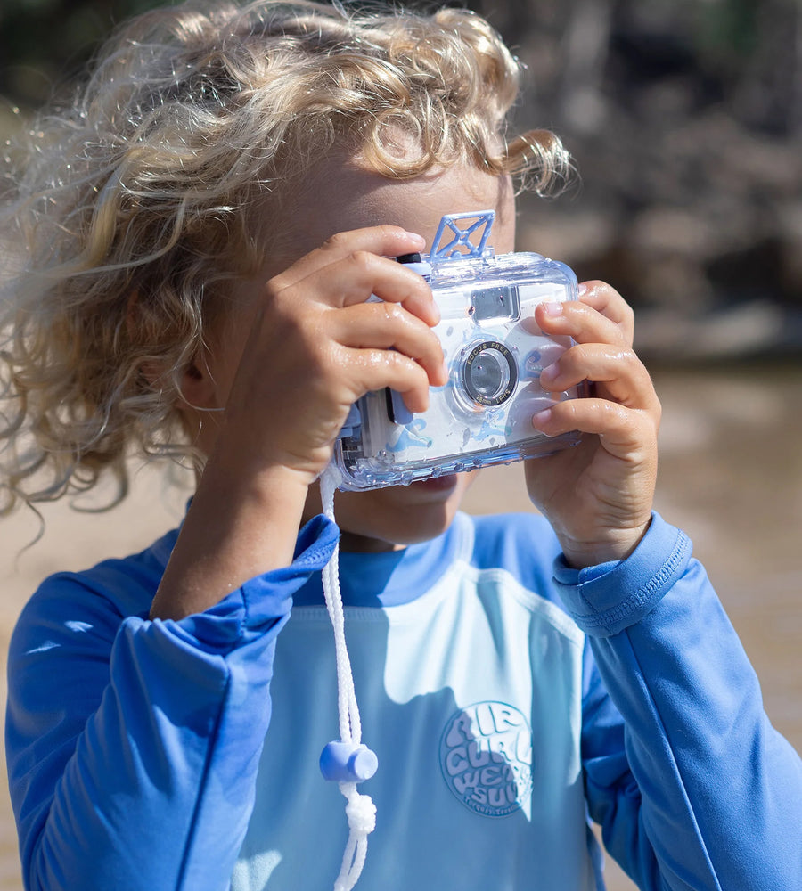 Child holding a clear camera up to their face with a natural background