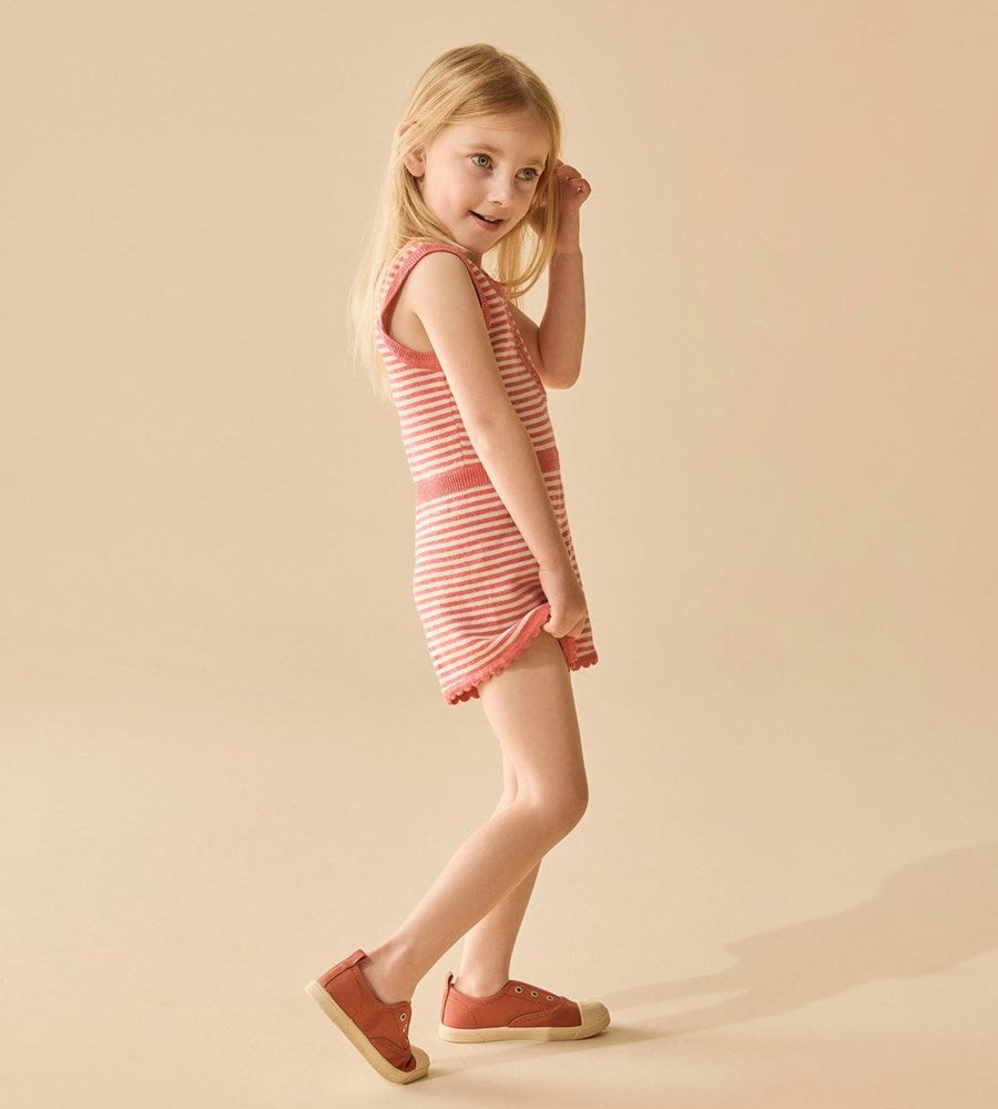 Young girl wearing a pink and white striped dress on a beige background