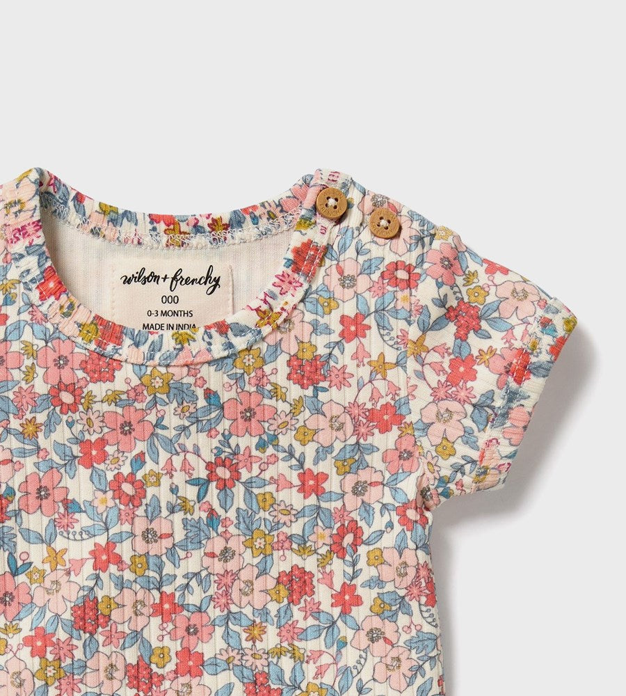 Floral baby romper with wooden buttons on a white background