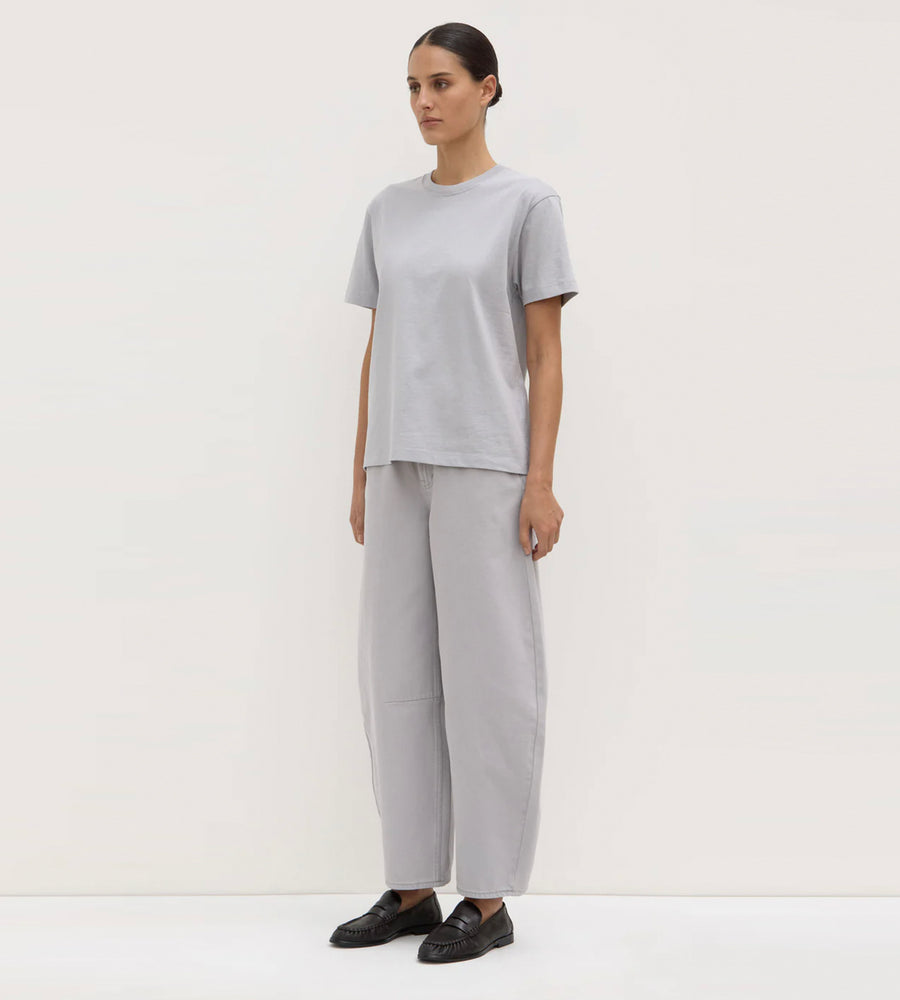 Person wearing a light gray outfit with wide-leg pants on a white background