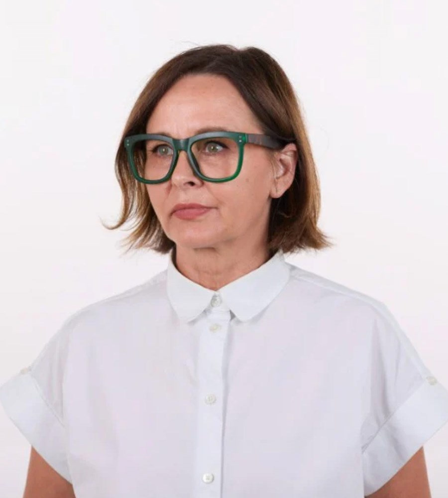 Person wearing green glasses and a white shirt on a white background