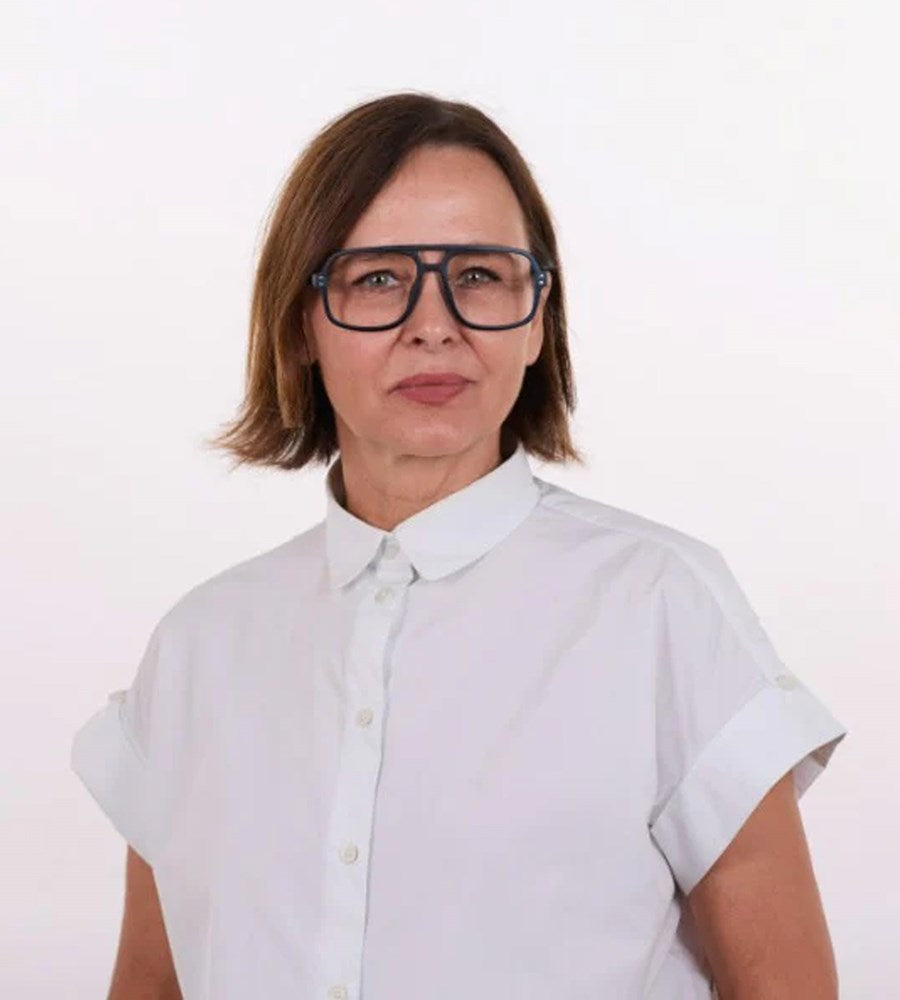 Person wearing a white shirt and large glasses on a plain background