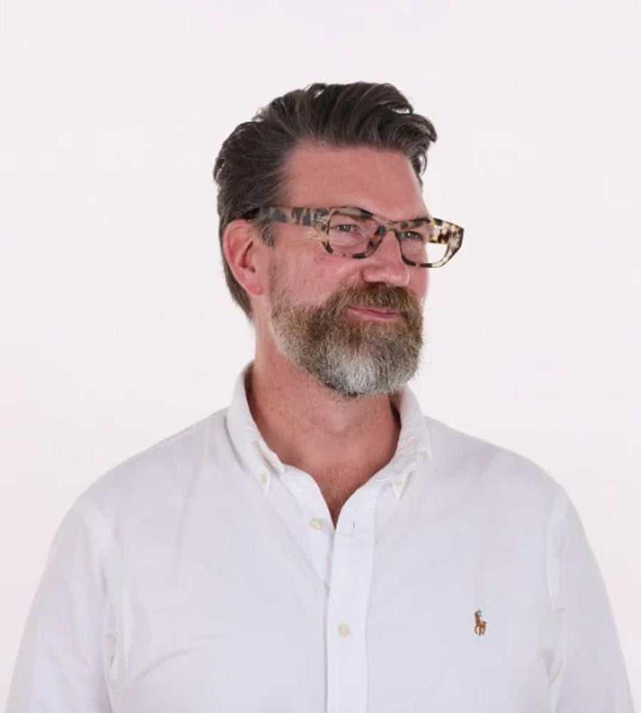 Man wearing glasses and a white polo shirt with a logo on a white background